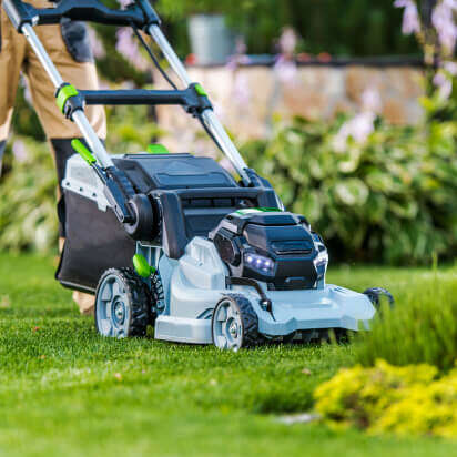 man cutting the grass in backyard garden using lawn mower and professional gardening tools