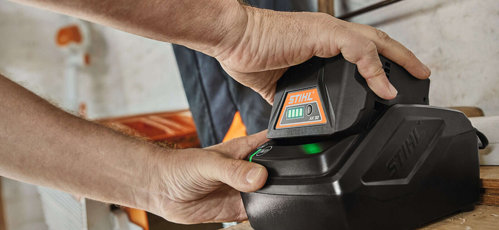 Person setzt STIHL Akku AK 30 in das Ladegerät ein.