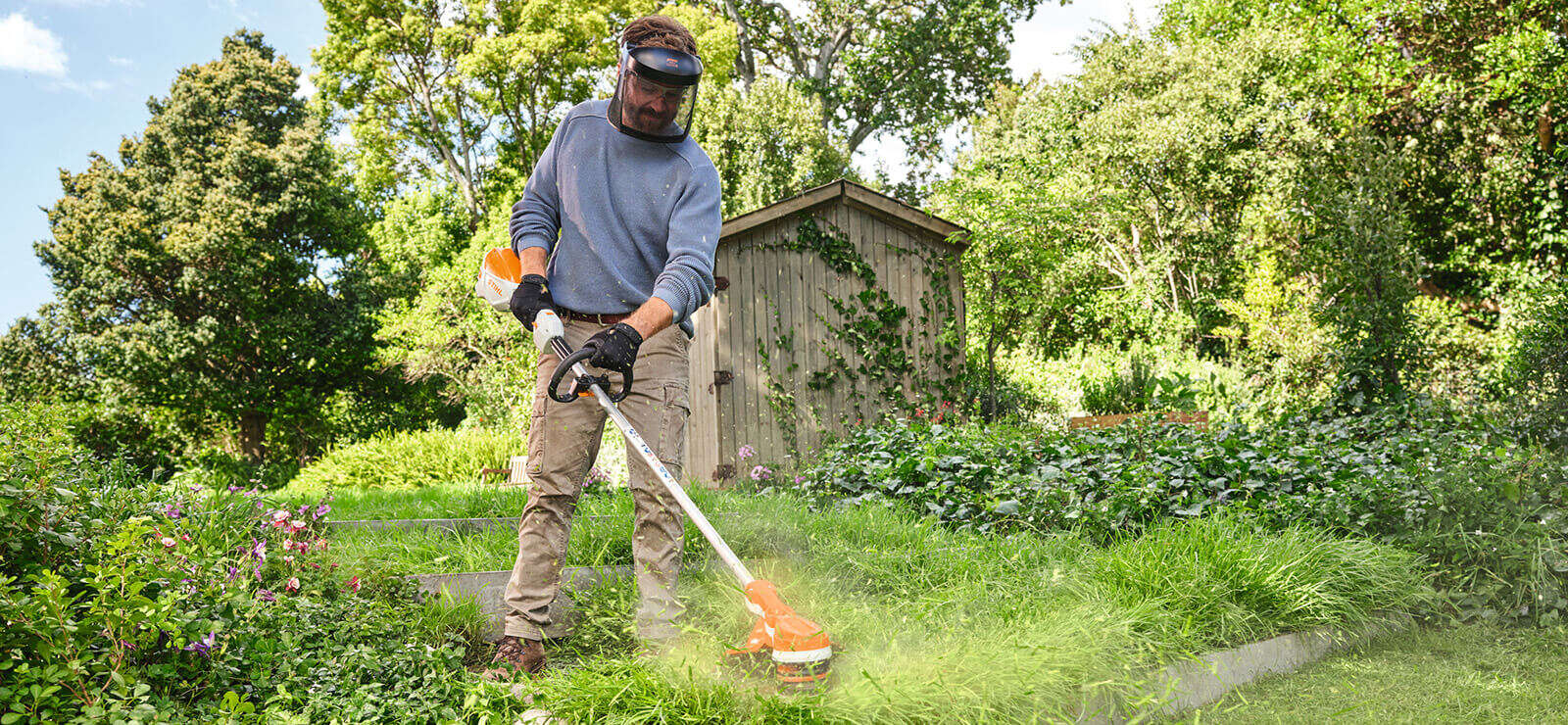 Mann trimmt Rasen mit STIHL Freischneider.