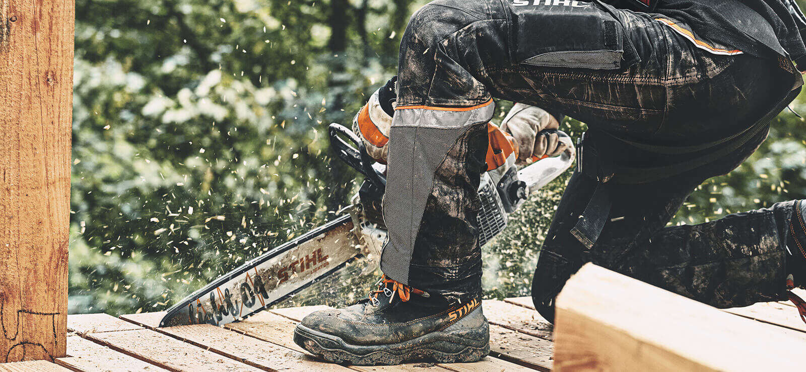 Mann sägt mit STIHL Kettensäge Holzplanken.