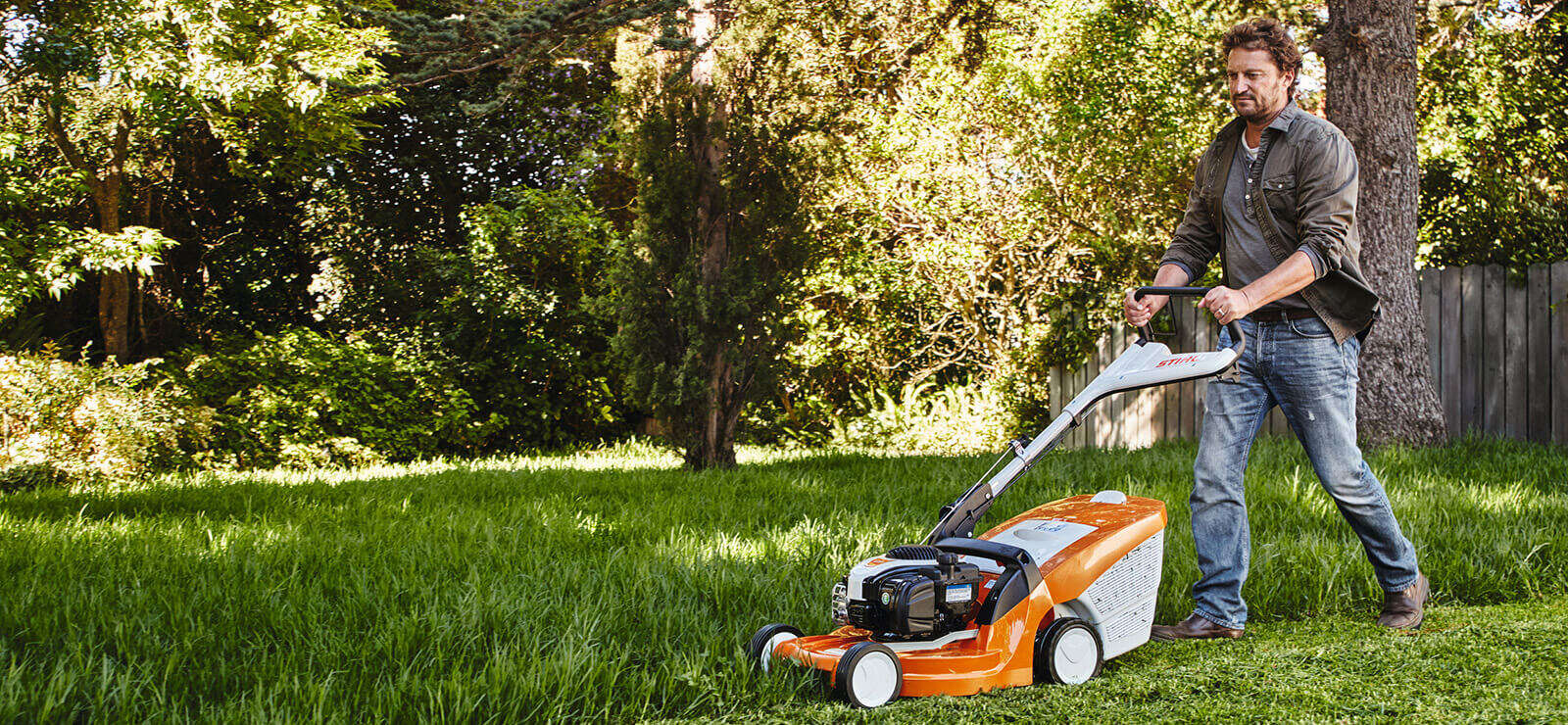 Mann mäht mit STIHL Rasenmäher den Rasen im Garten.